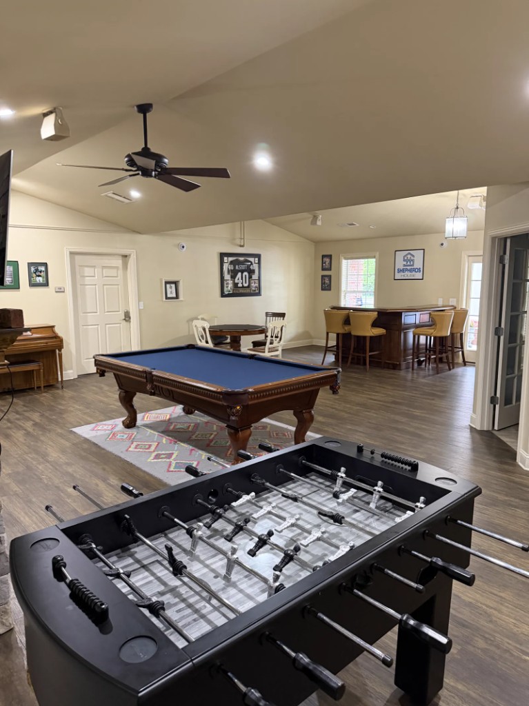 Lyndhurst recovery housing recreation room with pool table, foosball, and a framed Shepherd's House logo