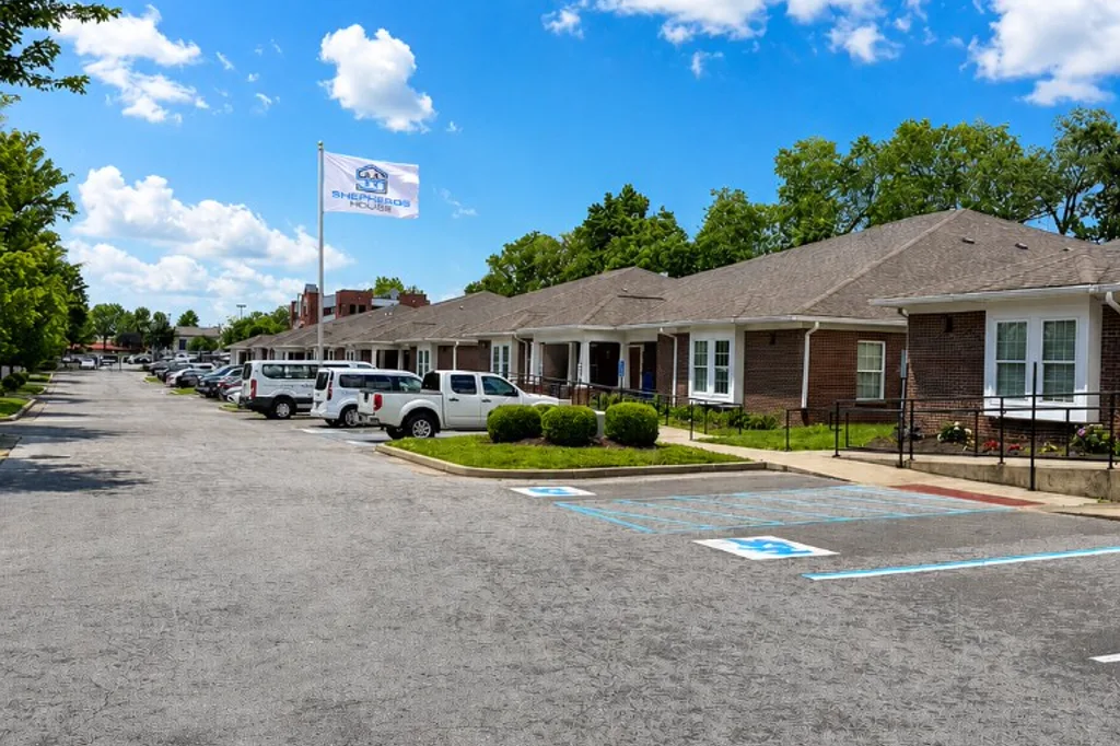 Shepherd's House recovery campus with a brick building, white-columned entries, and a flagged courtyard for the 12&ndash;18 month long-term recovery program